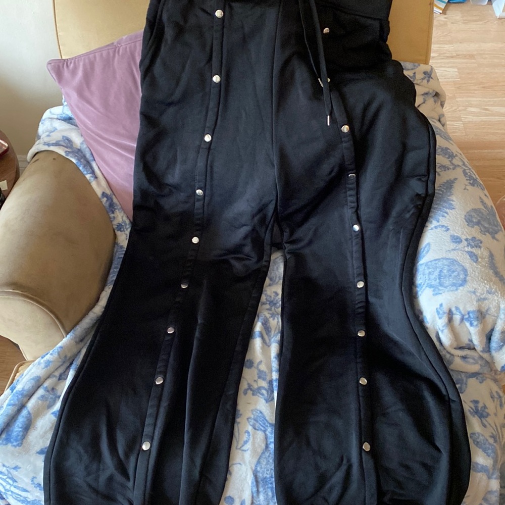 Black sweat pants with un-claspable buttons down each leg
